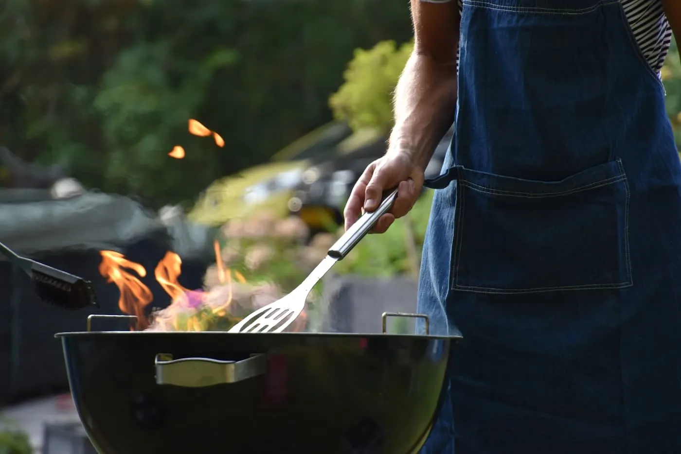 Outdoor pizza oven with wood stacked beside it and a gathering of friends around a backyard entertaining area