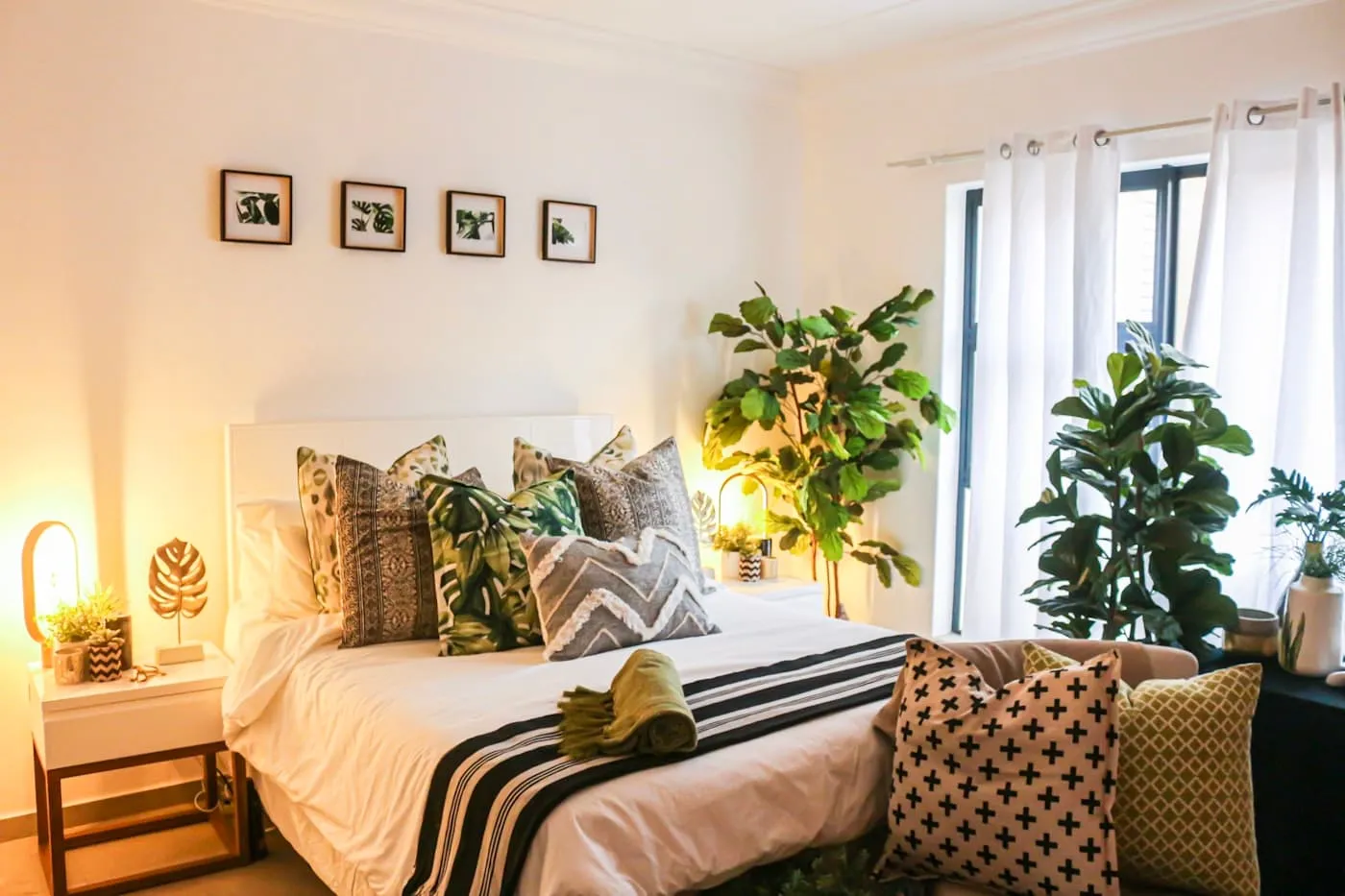 White ceramic plant pot with a trailing pothos beside a rattan bedside table in a coastal bedroom